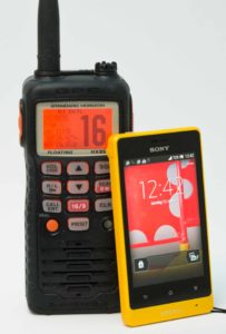 Bildet viser en vhf radio og en mobiltelefon