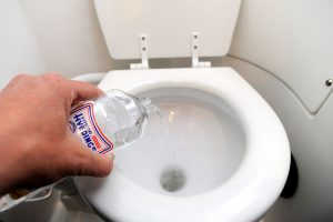 Bildet viser en hånd som rengjør toalett med eddik.