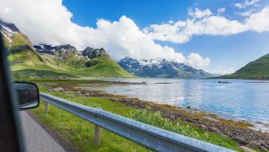 Avis og RS: Bilde av norsk natur med fjell og fjord sett fra passasjersetet i en bil.