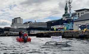 Bildet viser plastoppsamleren fra Clear Ocean som blir slepet rundt i Vågen i Bergen