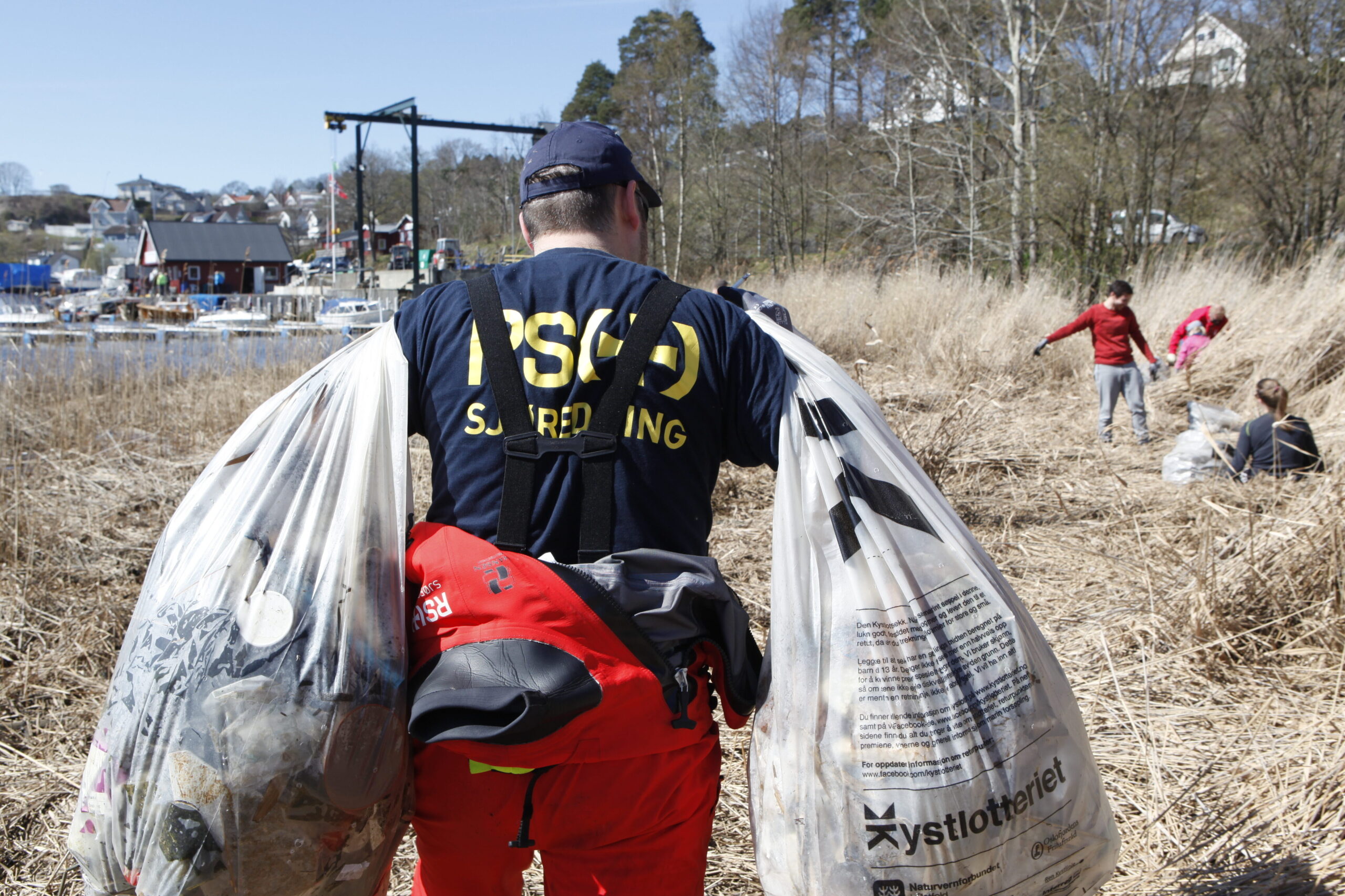 Bildet viser en redningsmann som rydder plast langs kysten